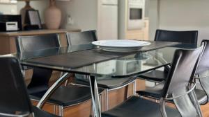 een glazen tafel met zwarte stoelen en een bord erop bij Plover Executive Deluxe Villa 25 in Cams Wharf