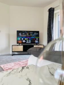 uma sala de estar com uma televisão e um sofá em Leicester City 4 Bed home em Leicester