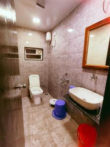 een badkamer met een wastafel, een toilet en een spiegel bij Aroma Residency in Mahabaleshwar