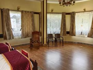 a bedroom with a bed and chairs and windows at Hillfort Hotels & Resorts Yelagiri in Yelagiri