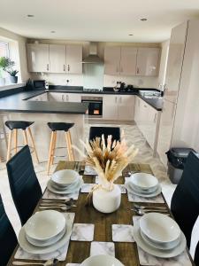 uma cozinha com uma mesa de madeira com placas e cadeiras em Leicester City 4 Bed home em Leicester