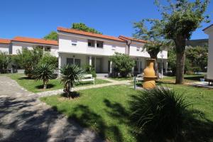 a white house with a yard with a yellow fire hydrant at Villas Corinthia in Baška