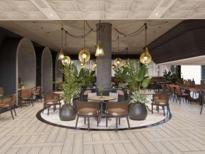un vestíbulo con mesas, sillas y plantas en Mövenpick Hotel Windhoek, en Windhoek