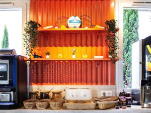 una cocina con cortina roja y cestas en una encimera en ibis budget Lunel Porte de Camargue, en Aimargues