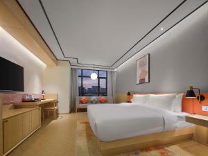 um quarto com uma grande cama branca e uma televisão em Hilton Garden Inn Aksu Downtown em Aksu