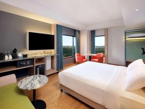 ein Hotelzimmer mit einem großen Bett und einem TV in der Unterkunft ibis Styles Serpong BSD City in Tangerang
