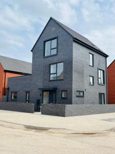 uma casa de tijolos cinzentos com janelas numa rua em Leicester City 4 Bed home em Leicester