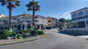 eine Straße in einer Stadt mit Palmen und olympischen Ringen in der Unterkunft Sausset-les-Pins, T2 vue sur mer, plage à 200m in Sausset-les-Pins