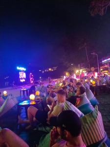 a crowd of people sitting on beach chairs at night at Haadrin village Fullmoon in Haad Rin