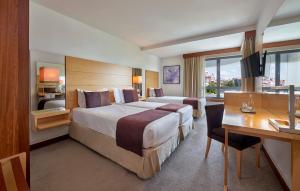 ein Hotelzimmer mit einem großen Bett und einem Schreibtisch in der Unterkunft Hotel Acores Lisboa in Lissabon