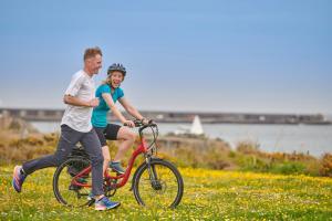 un hombre y una mujer montando una bicicleta en un campo en Braye Beach Hotel, en Braye