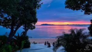 - un coucher de soleil sur la plage avec des personnes se promenant sur la plage dans l'établissement Miavaka Lodge, à Ambatobe