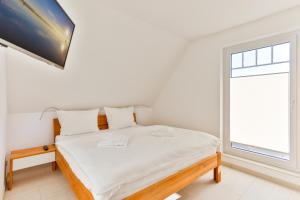 a white bedroom with a bed and a window at Landhaus Wreechen mit Dachterrasse in Putbus