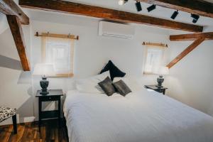 a bedroom with a white bed with two tables and two windows at Weingut Holler Chalet Weingarten in Spielfeld +21 photos