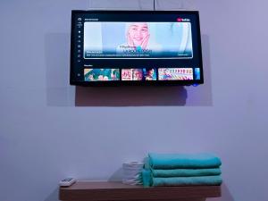 a flat screen tv hanging on a wall with towels at BMW Hotel in Muar