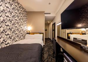 a hotel room with two beds and a flat screen tv at APA Hotel Kanazawa-nishi in Kanazawa