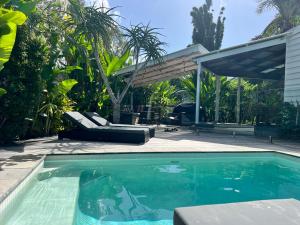 a swimming pool in front of a house with a patio at Bamboo Beach House & Studio in Byron Bay