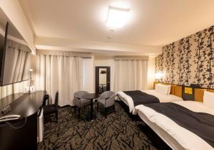 a hotel room with two beds and a table at APA Hotel Kanazawa-nishi in Kanazawa