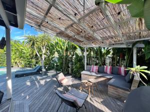 a patio with a couch and chairs under a pergola at Bamboo Beach House & Studio in Byron Bay