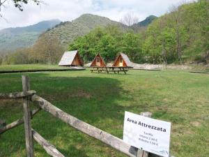 duas tendas num campo com uma cerca e uma placa em Parco Archeologico Valdieri em Valdieri