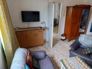 een woonkamer met een bank en een tv bij Open Air Café & Apartment 1 in Port Louis