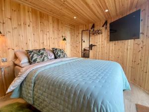 a bedroom with a large bed with a tv on the wall at Silo Green in Great Dunmow