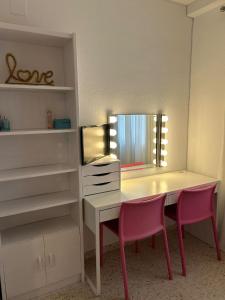 マイレナ・デル・アルハラフェにあるHabitación Cuki , baño privadoの机とピンクの椅子2脚が置かれた更衣室