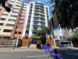 un edificio alto con una cinta azul delante de él en Habi baño Compartido Grimaldo 1 en Lima