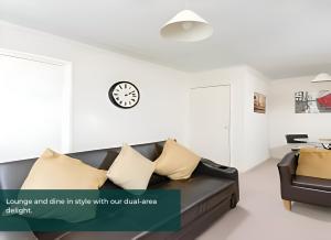 uma sala de estar com um sofá e um relógio na parede em Clarence Suite - Free Parking em Chatham