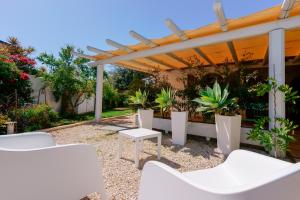 un patio con sillas blancas y pérgola en Villamarina42, en Flumini di Quartu