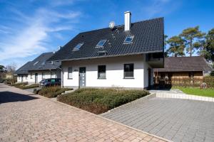 a white house with a black roof at Strandhaus 3 EG in Röbel