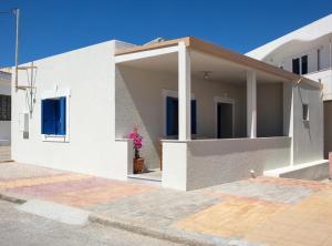 een wit huis met blauwe luiken op een straat bij stonehousekefalos in Kefalos