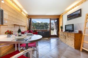 een woonkamer met een tafel en een televisie bij Résidence Grands Montets 133 ski in-ski out - Happy Rentals in Chamonix-Mont-Blanc