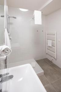 a white bathroom with a shower and a sink at Motel24seven in Bruck an der Mur