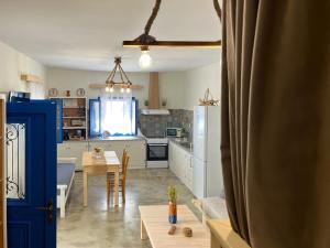 een keuken en een woonkamer met een tafel en een blauwe deur bij stonehousekefalos in Kefalos
