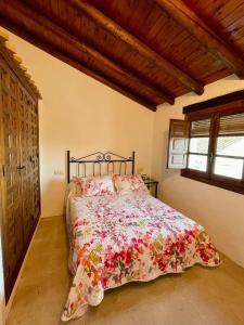 a bedroom with a bed with a floral bedspread at Casa Molino de los Patos in Yunquera