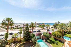 an apartment with a pool and palm trees and the ocean at TrendyHomes Puerto - Vistas al mar, parking incluido, playa a un paso in Aguadulce