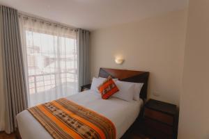 um quarto com uma cama grande e uma janela em Quechua ApartHotel em Cusco
