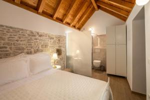 a bedroom with a white bed and a stone wall at Villa Casa di Perla in Primošten +67 photos