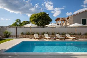 a swimming pool with lounge chairs and umbrellas at Villa Casa di Perla in Primošten