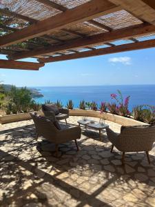 eine Terrasse mit Stühlen, einem Tisch und Meerblick in der Unterkunft villa bella vista in Zambrone