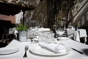 una mesa con platos blancos y copas de vino. en Hacienda la Coracera, en San Martín de Valdeiglesias