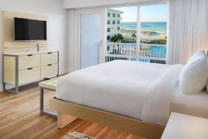 a bedroom with a bed and a television and a balcony at SpringHill Suites by Marriott Pensacola Beach in Pensacola Beach
