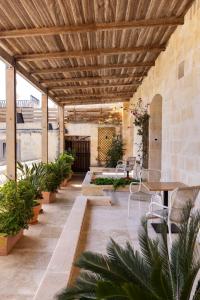 an outdoor patio with tables and chairs and plants at The Xara Palace Relais & Chateaux in Mdina