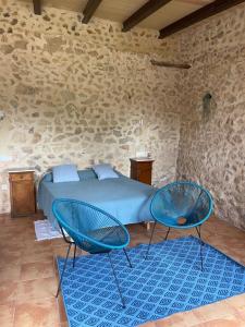 a bedroom with a bed and two blue chairs at Agroturismo Finca Dalt Murada in Binissalem