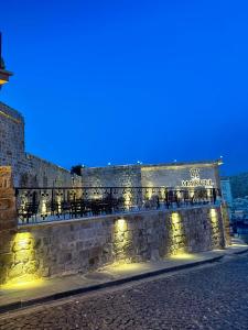 a building with tables and chairs on a wall at night at Marvel Hotel in Mardin