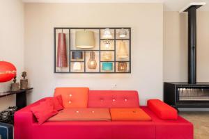 a red couch in a living room with a shelf at Le Mas - House with swimming pool in a privileged environment in Saint-Didier-au-Mont-dʼOr