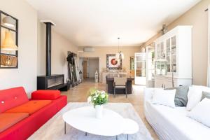 a living room with a red couch and a white table at Le Mas - House with swimming pool in a privileged environment in Saint-Didier-au-Mont-dʼOr +37 photos