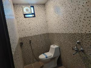 W wyłożonej kafelkami łazience znajduje się toaleta i prysznic. w obiekcie Coastal Grand Hotel Sampath w mieście Tiruchchirāppalli