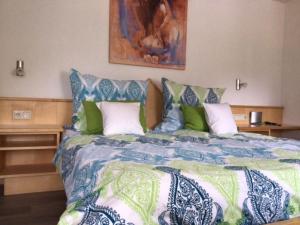 a bedroom with a large bed with blue and green sheets at Gasthof Alpenblick in Tobadill